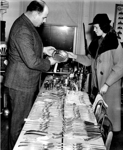 Police lieutenant and woman inspecting stolen silverware